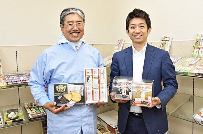 竹内製菓グループの製品を持つ清水氏(右)と荒井氏(左)